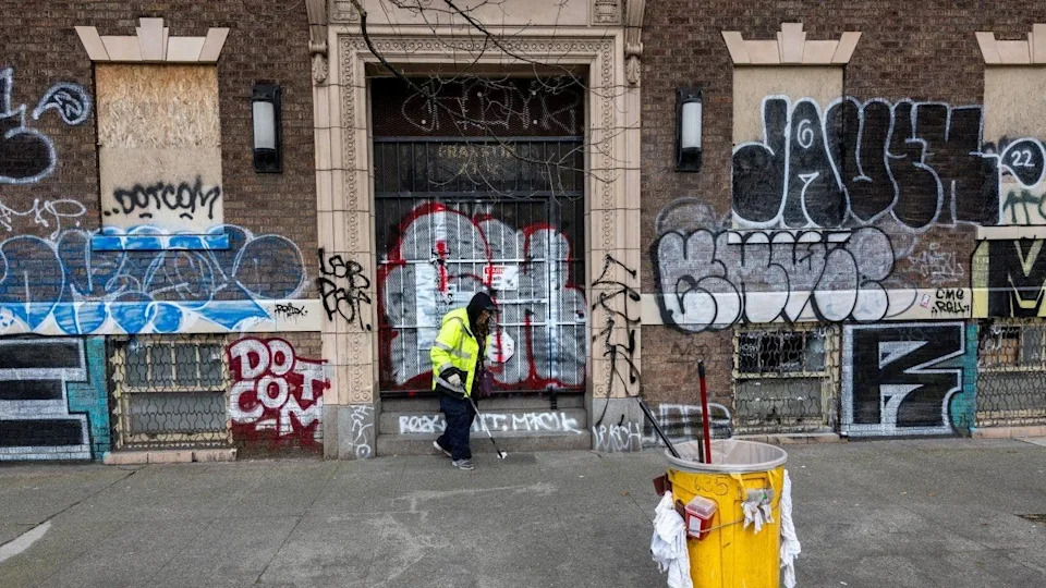 City worker picking up trash next to graffiti on 4th Avenue in Seattle