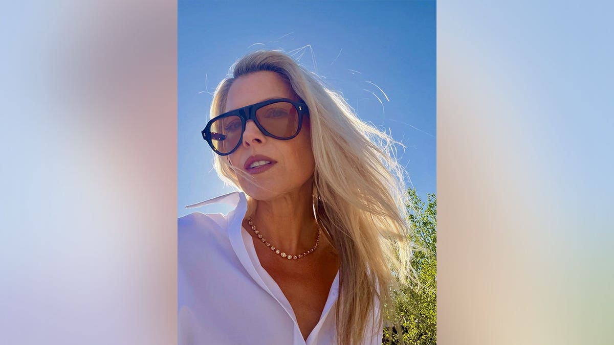Ali Larter posing with dark sunglasses and a white shirt in May 2026.