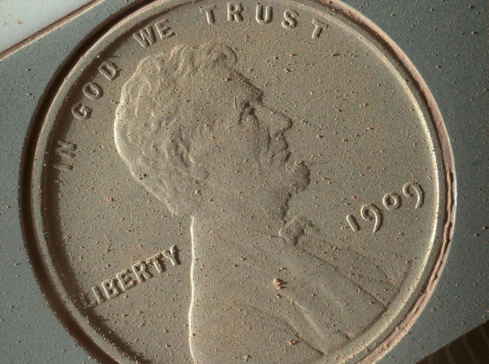 A close-up of the heads side of a penny covered in Mars dust.