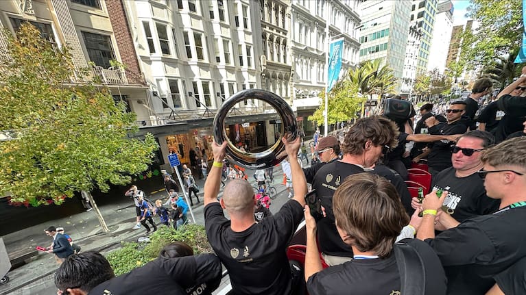 Auckland FC player waves trophy at fans.