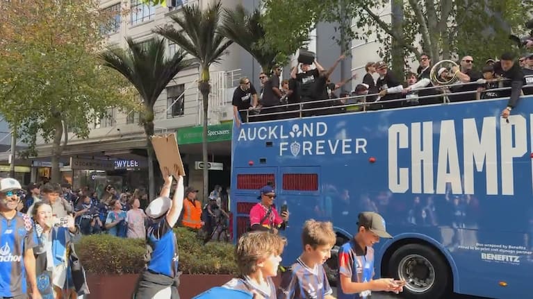 Auckland FC players parade in open-top bus.