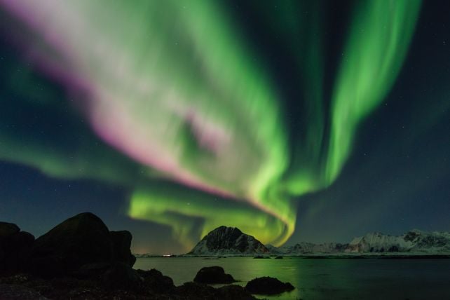 A dazzling green aurora seen over an ocean 