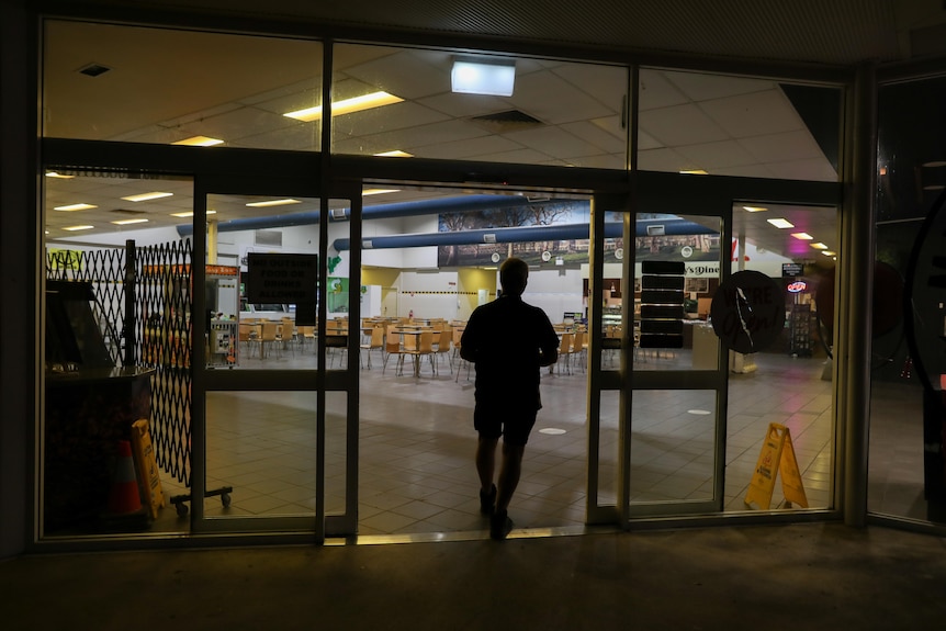 The silhouette of a man is seen as he walks into a truck changeover premises at night for a break.