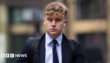 Lewis Rollins wearing a black suit walking into court.