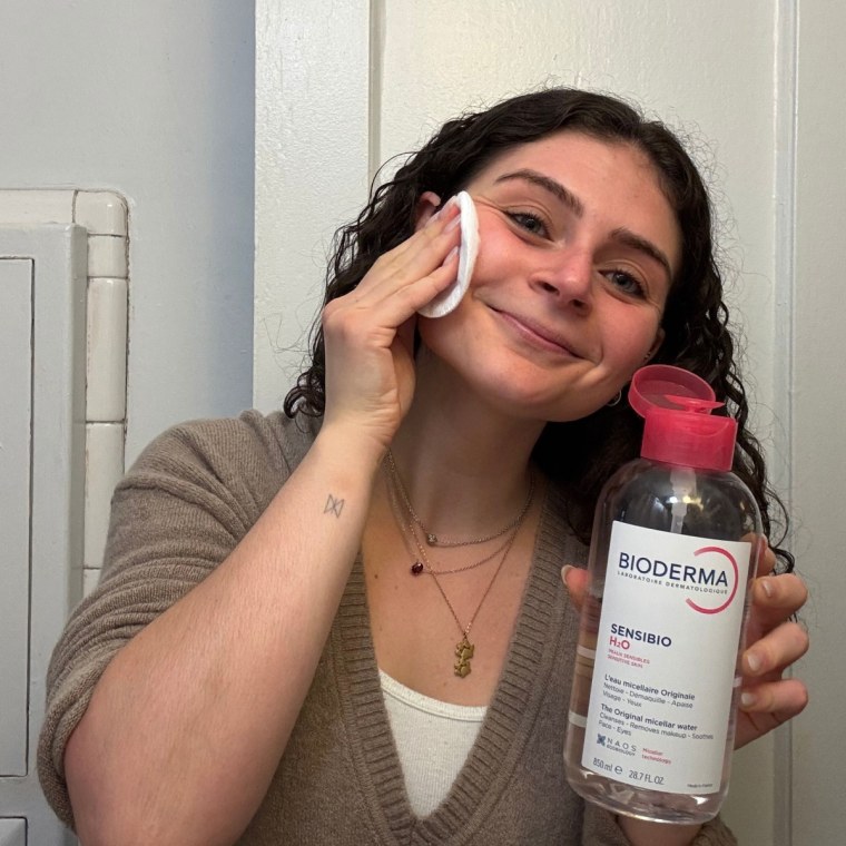 A woman applying Bioderma’s Sensibio Micellar Water to her skin.