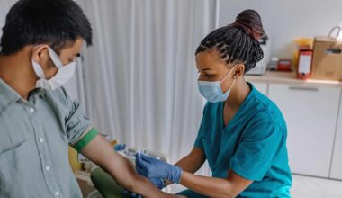 a nurse wearing a medical mask prepares a patient for a blood donation in a surgical setting.