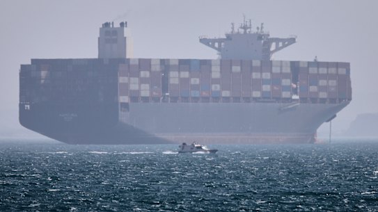 A container ship sits at anchor as a small motorboat passes in the foreground in the Strait of Hormuz on Saturday.