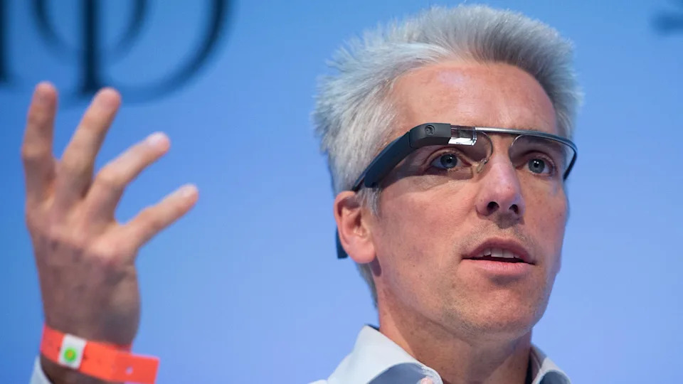 A man on stage wearing Google's initial attempt at smart glasses, which feature a prominent wire across the brow and a small camera in fromt of one eye.