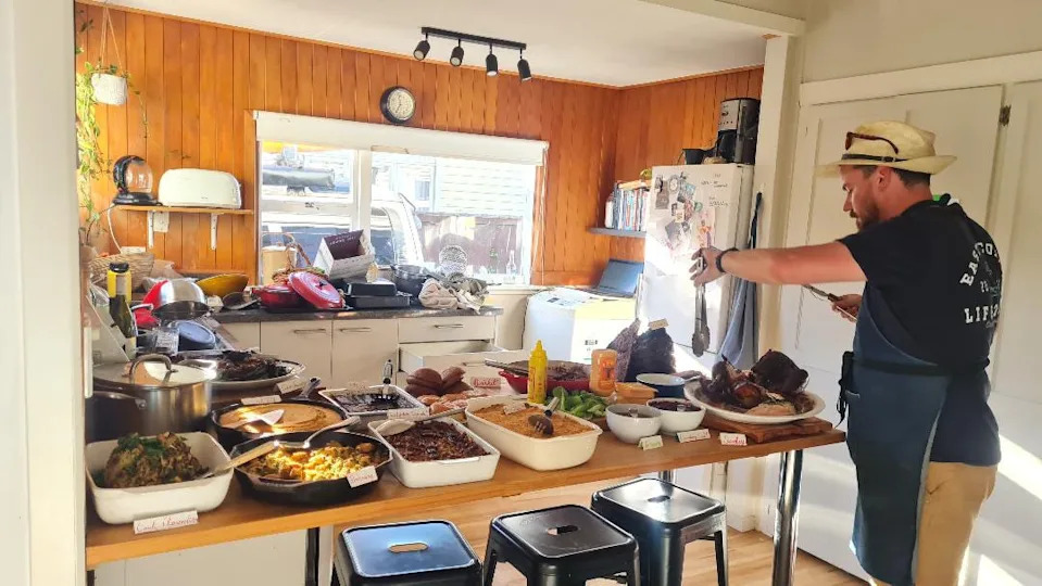 The author's husband helps prepare to host a Thanksgiving dinner at their home in New Zealand.