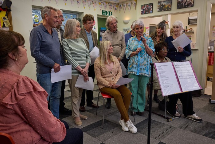 Debbie grins as she stands among the choir members in Coronation Street