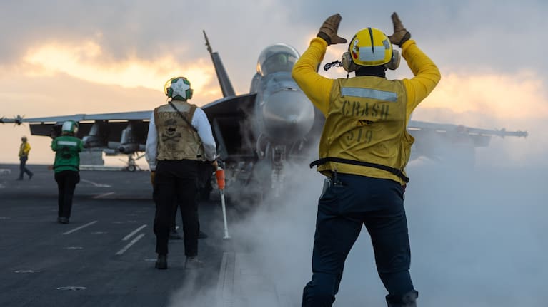 Crew with a fighter jet on a US Navy aircraft carrier.
