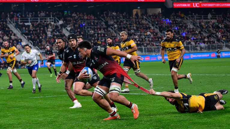 Crusaders loose forward Christian Lio-Willie has the shirt ripped off his back by a Hurricanes defender at Te Kaha.