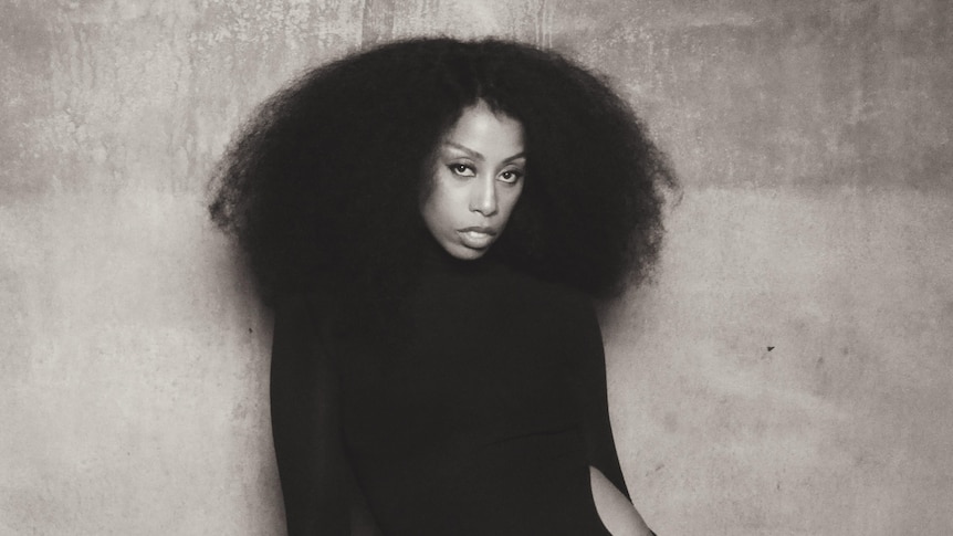 Black-and-white portrait of Rochelle Jordan in a flowing dress against a textured wall.