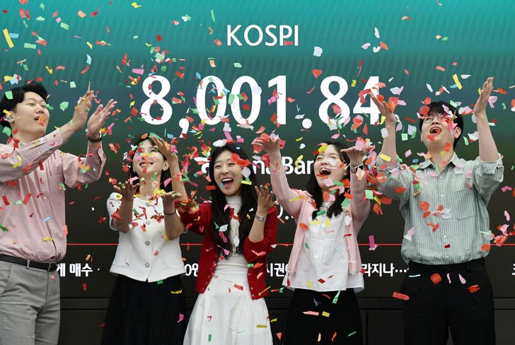 Dealers at Hana Bank headquarters in Seoul celebrate after the benchmark KOSPI crossed the historic 8,000 mark for the first time during intraday trading, May 15. Yonhap