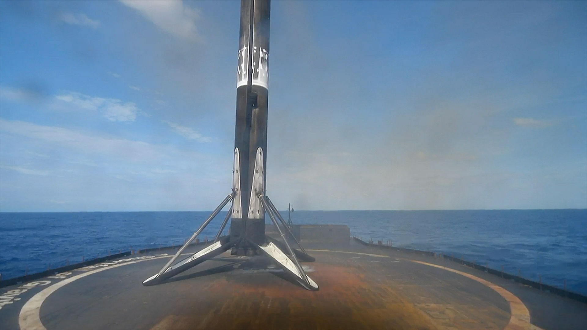 The first stage of an orbital rocket stands atop a platform in the ocean after landing on its four deployed legs.