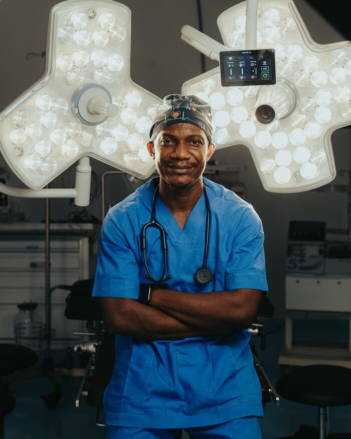 Medical worker in scrubs and cap standing confidently in operating room