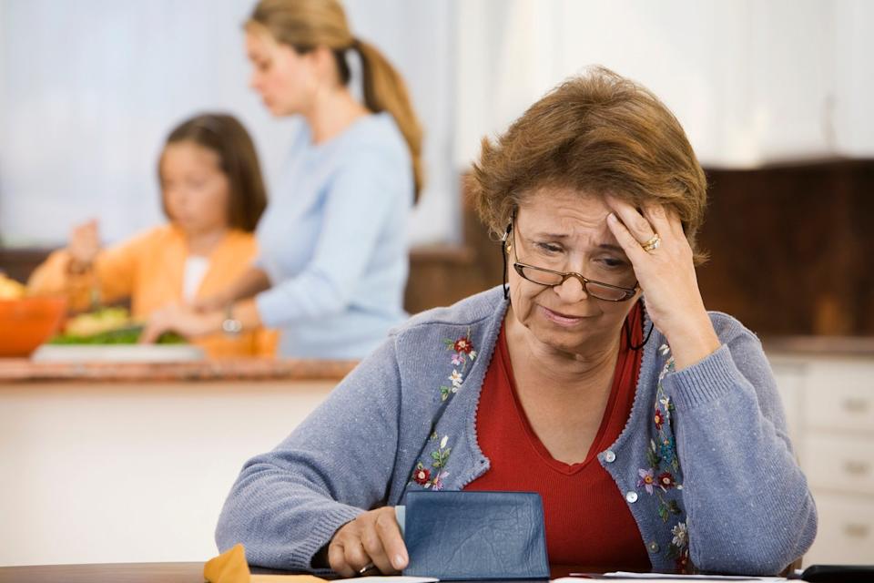 A person looks worried while holding a checkbook.