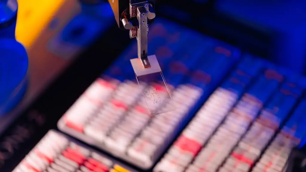 Close-up of a robotic arm holding a glass microscope slide above rows of blurred laboratory sample trays under blue and pink lighting, suggesting an automated digital pathology setting.