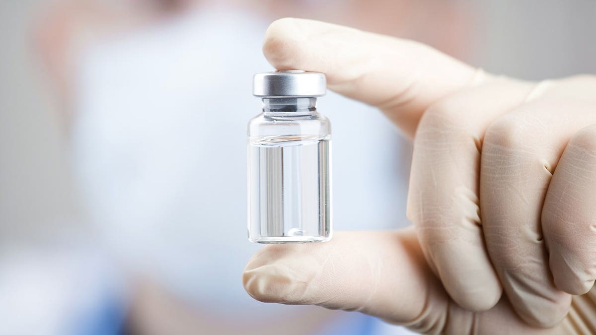 A doctor holding a vial and syringe preparing for injection