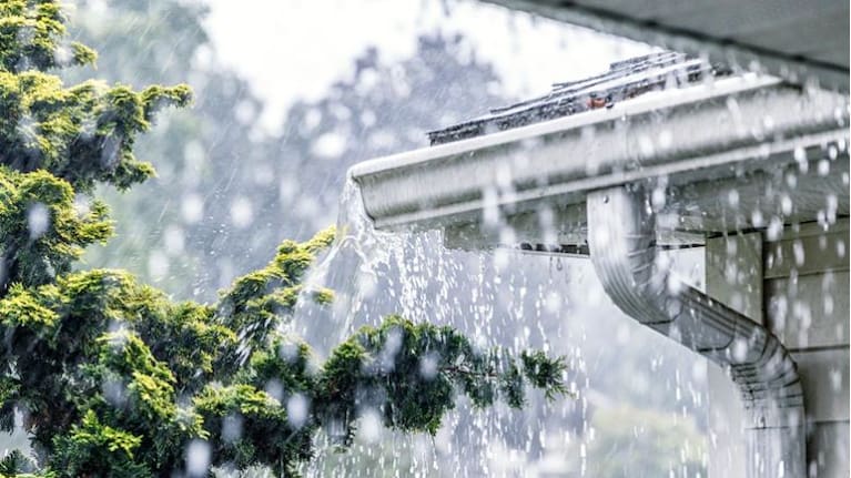 Drenching downpour rain storm water is overflowing off the tile shingle roof.