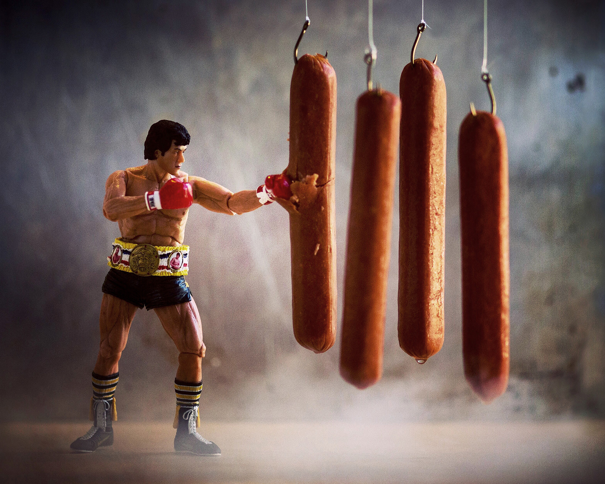 Action figure of a boxer punching a hanging sausage, with three other sausages hanging nearby