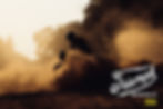 A Triumph Scrambler in silhouette riding in the dust.