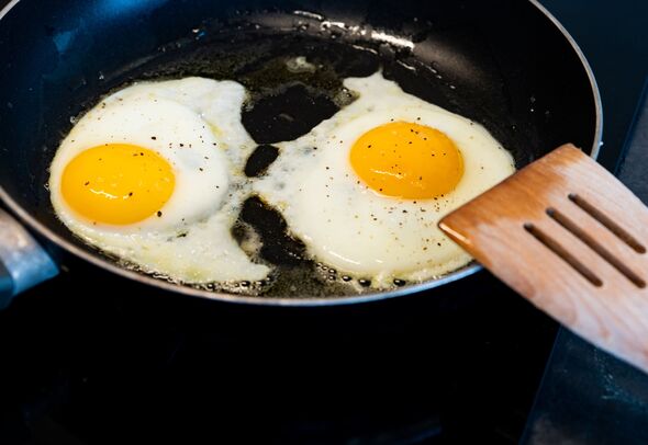 skilled with fried eggs and wooden s poon skilled with fried eggs and wooden s poon