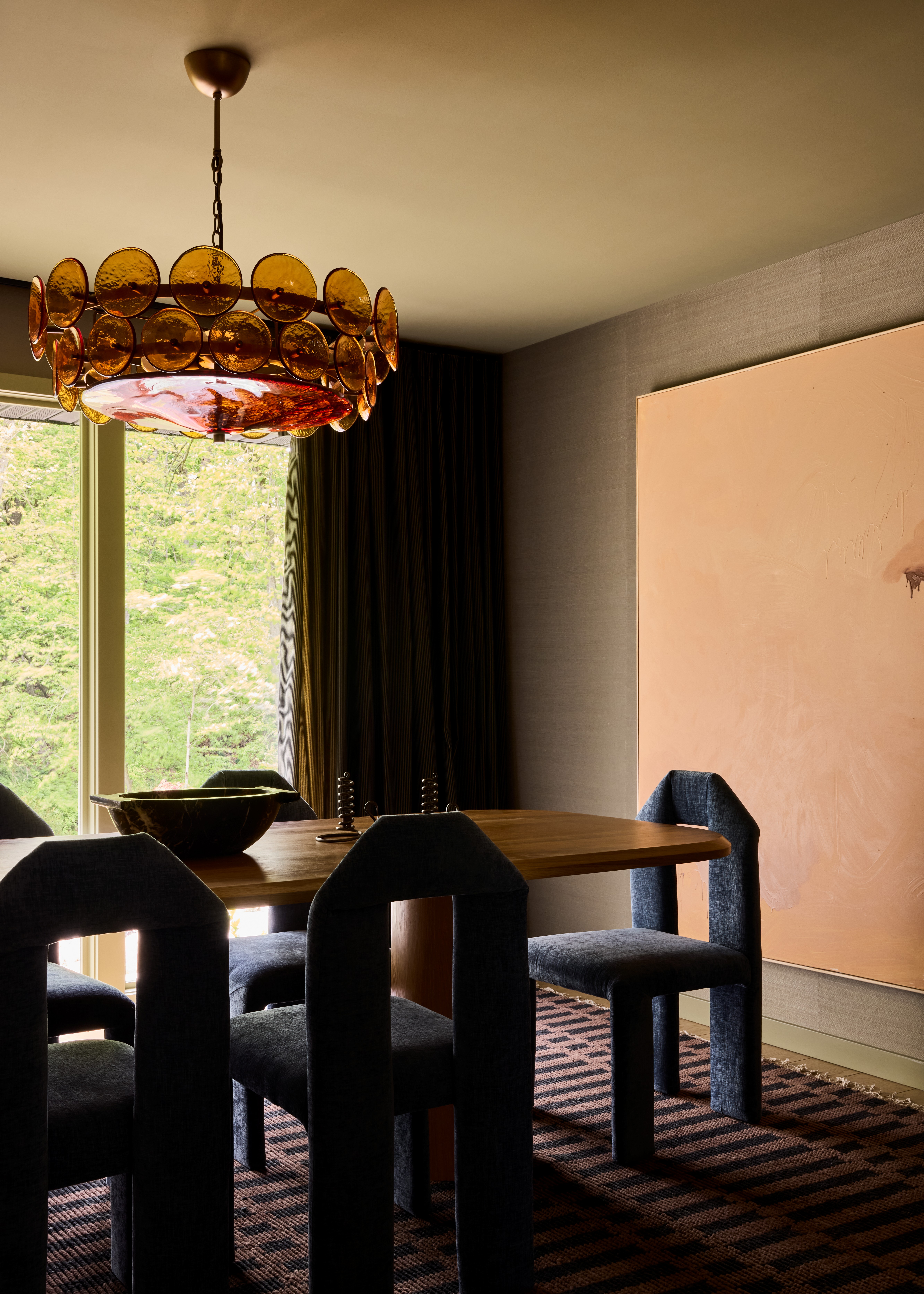 Interior shots depicting an apartment decorated with sculptural furnishings in earthy tones, framed artworks, marble and wood countertops, all bathing in natural light.