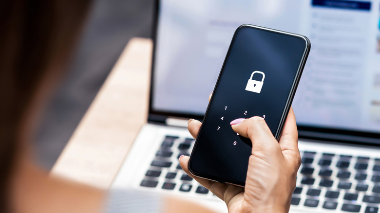 a person holding a phone with a lock symbol on the screen and number pad