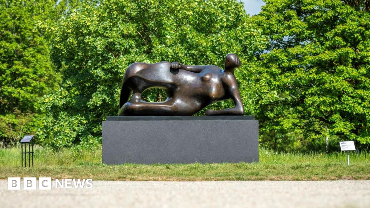 Henry Moore's statue Reclining Woman: Elbow on a patch of grass next to a path.