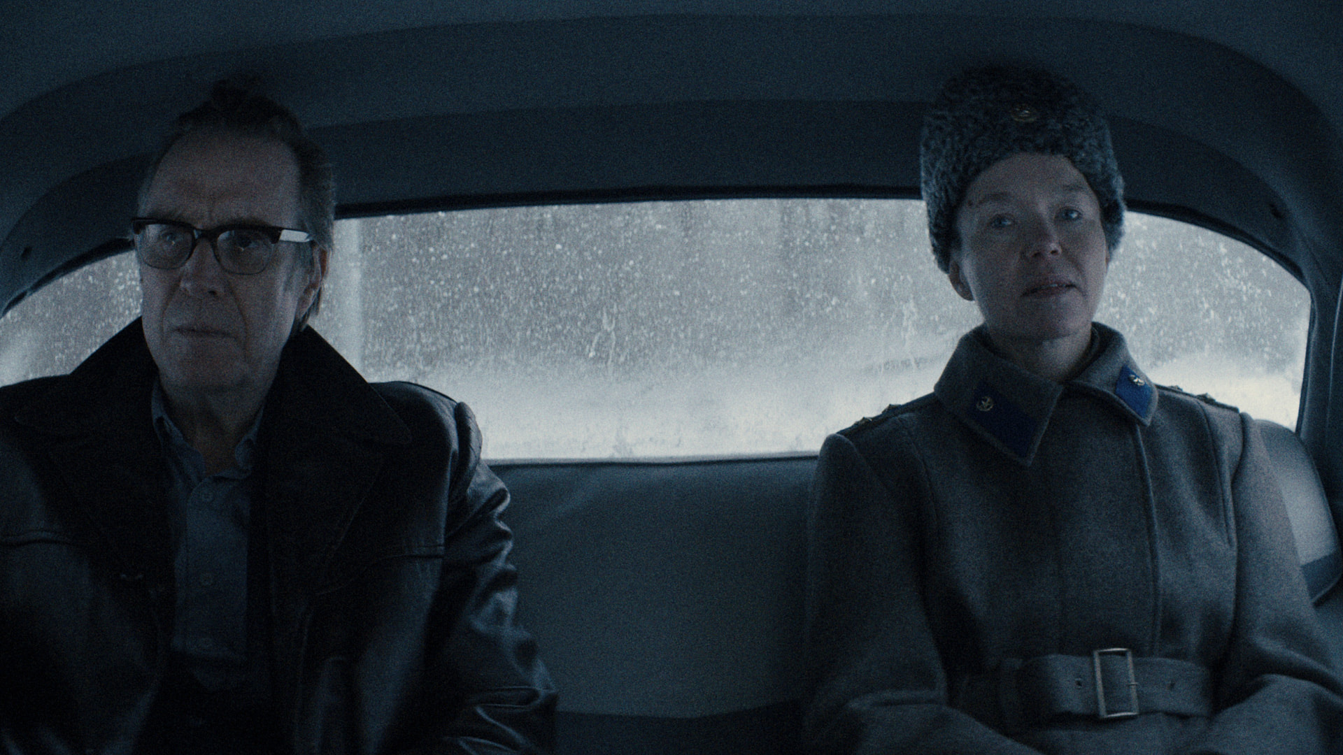 a man and woman sit silently in the back of a car