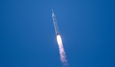 a white rocket launches into a cloudless blue sky