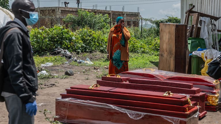 Family members of people who died of Ebola stand next to coffins at a health center in Rwampara, Congo.