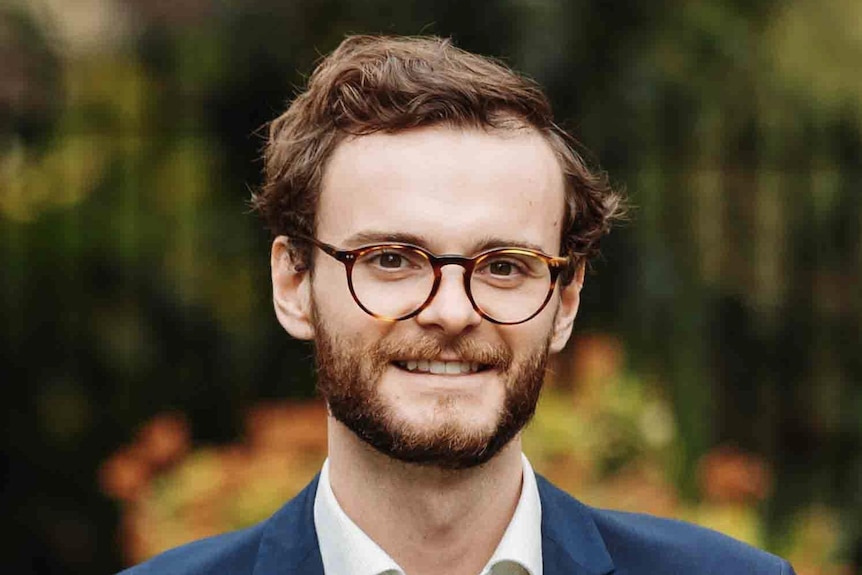 A man with glasses wearing a suit with no tie