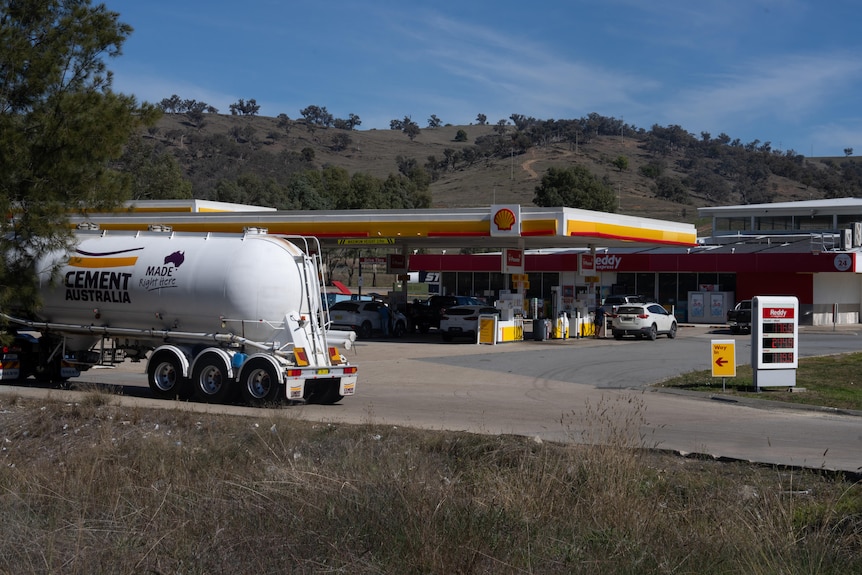 Trucks and cars pull into a Shell service station on a clear blue day.