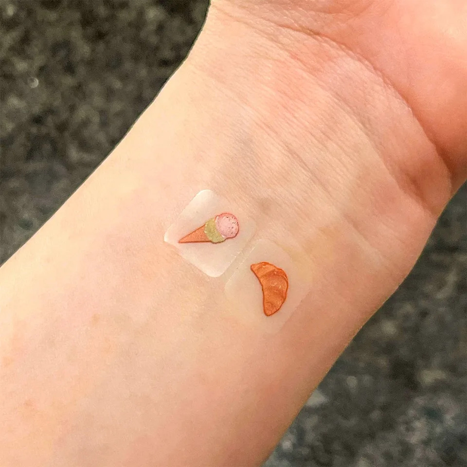Temporary tattoos of food items on a wrist.