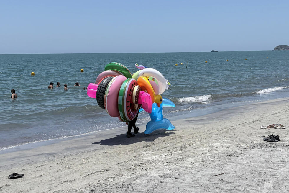 A seller of inflatable floats walks along the beach in Santa Marta, a major Colombian tourist destination, where violence lurks beneath the surface