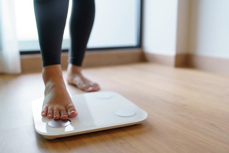 Person stepping on a bathroom scale.