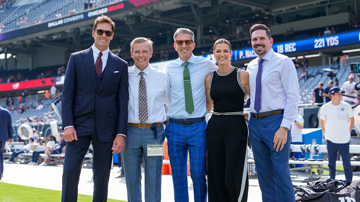 Fox Sports broadcast team including Tom Brady, Tom Rinaldi, Kevin Burkhardt, Erin Andrews, and Dean Blandino posing at Soldier Field