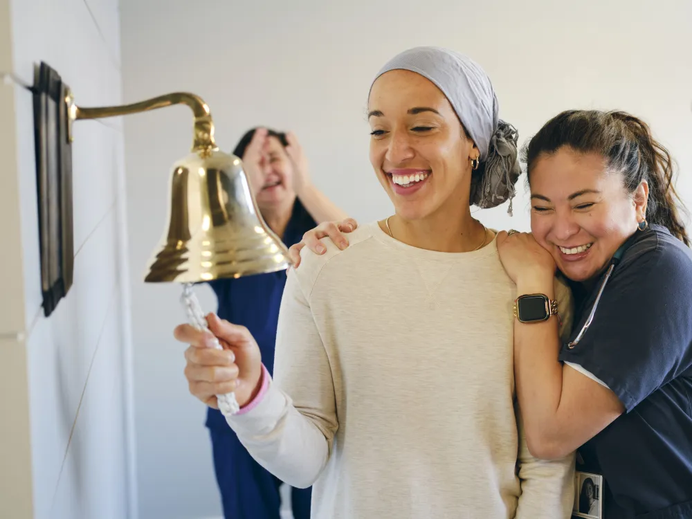 a woman rings a bell with nurses celebrating