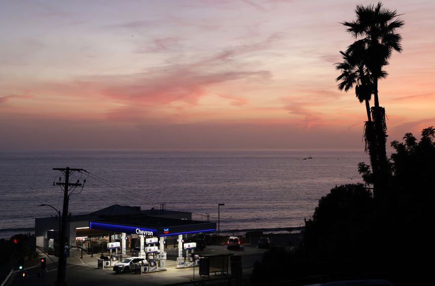 The sun sets beyond a gas station near the Pacific Ocean in El Segundo, California.