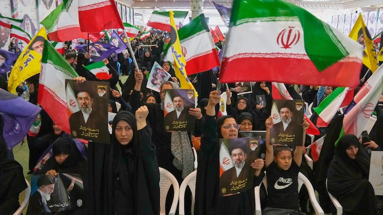 Government supporters hold Iranian flags and pictures of Iran's Supreme Leader, Ayatollah Mojtaba Khamenei