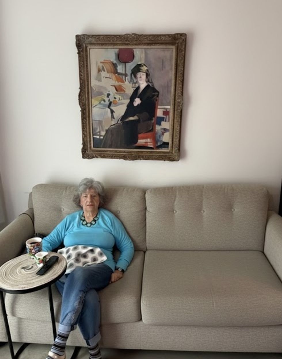 Helene Plotkin sitting on a sofa, with the FCB Cadell painting on the wall behind her