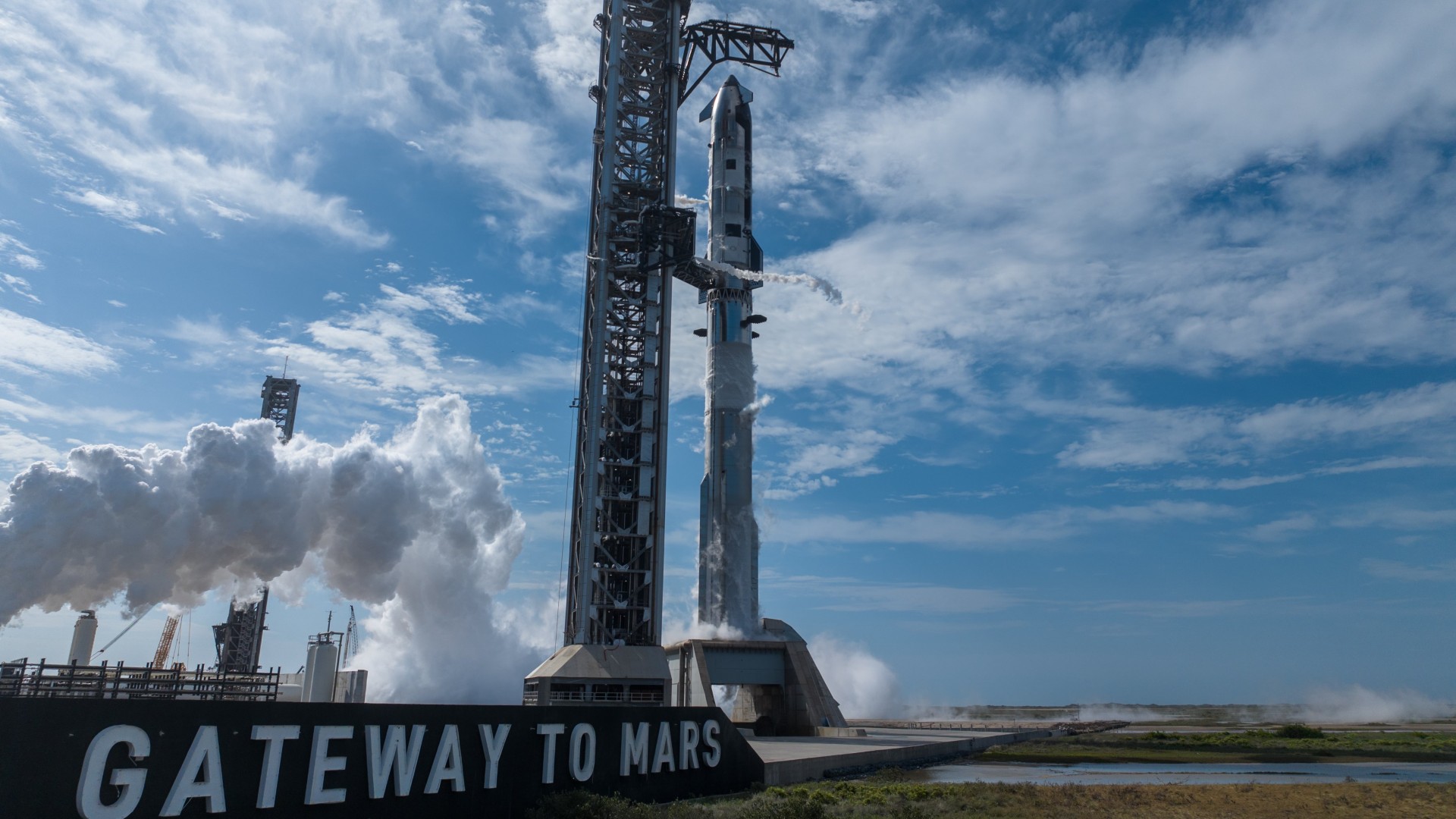 SpaceX's Starship Flight 12 Ship and Super Heavy booster on the pad by a Gateway to Mars sign.