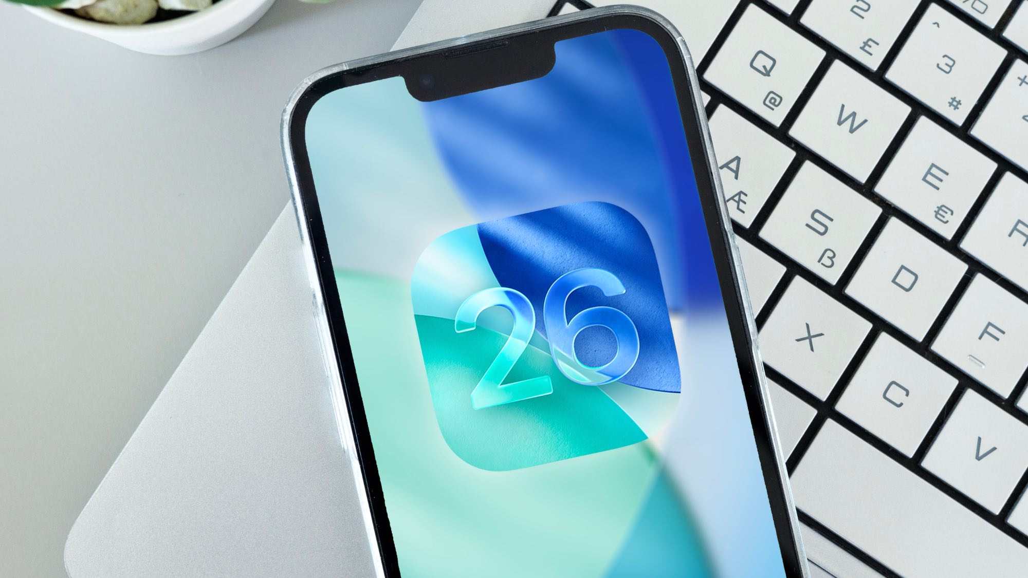 iOS 26 logo on iPhone sitting on a laptop keyboard