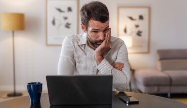 A man looking at his laptop in a stressed and upset manner