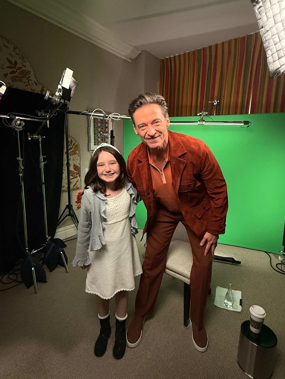 Hugh Jackman and a girl in front of camera equipment and a green screen