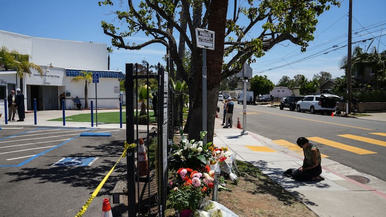 A person prays beside flowers outside the Islamic Center of San Diego, a day after the shooting.