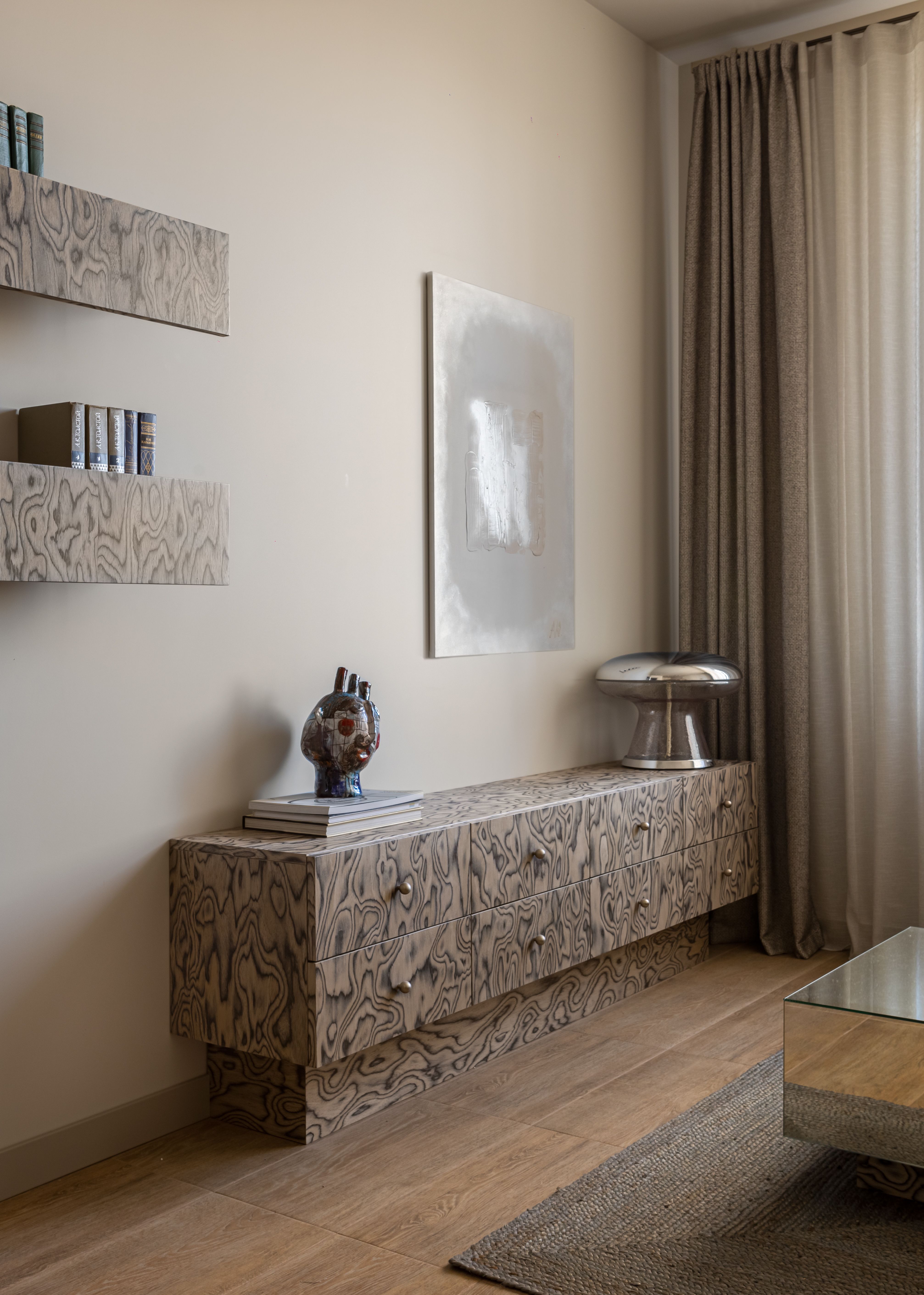 A small living room with a steel coffee table, a neutral couch and a console made in veneer 