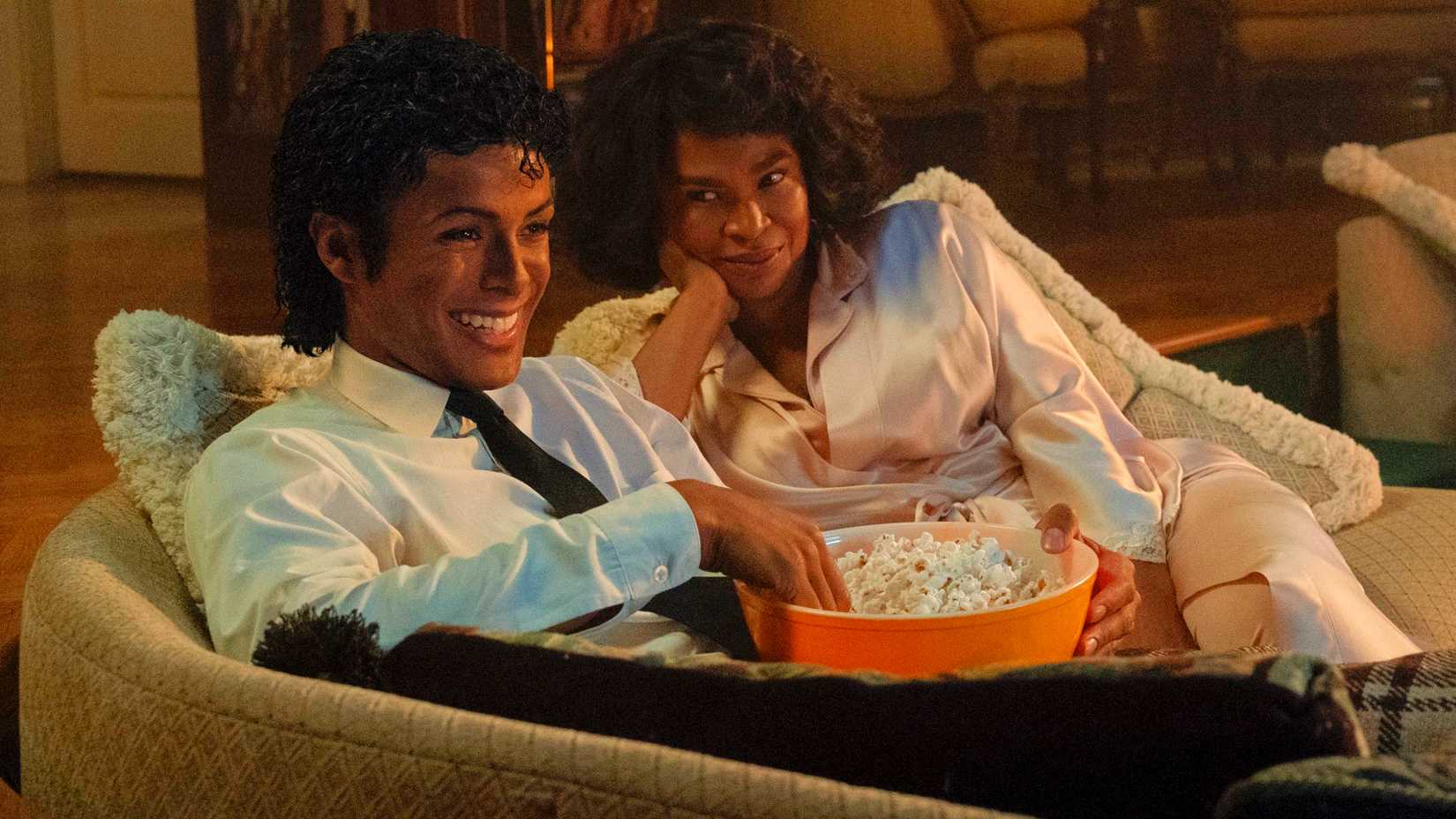 Jaafar Jackson as Michael Jackson eating popcorn on the couch with Nia Long as Katherine Jackson in Michael 2026